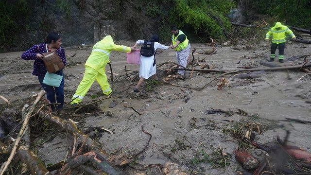 People try to cross a highway blocked by a landslide triggered by Hurricane Otis near Acapulco, Mexico 
